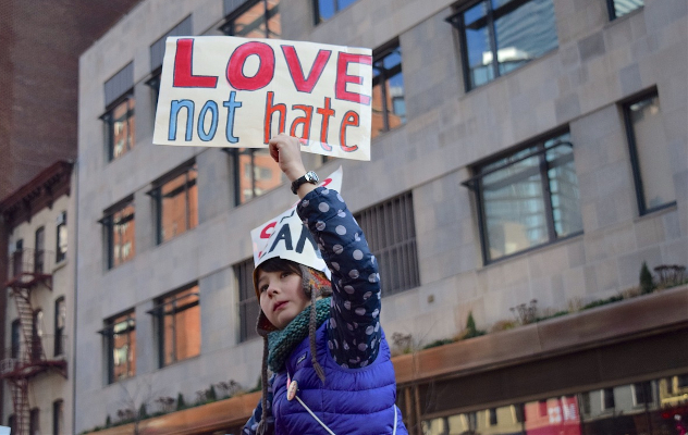 a young woman holding up a sign that reads: Love not Hate