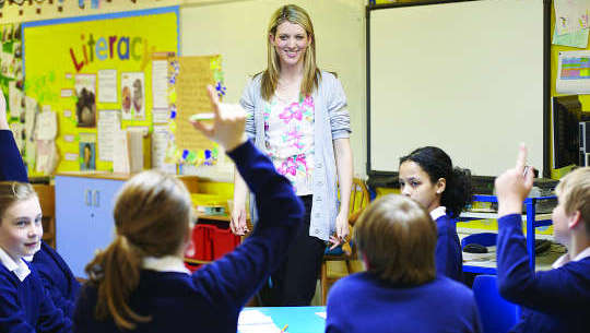 teacher standing in front of students in an open classroom