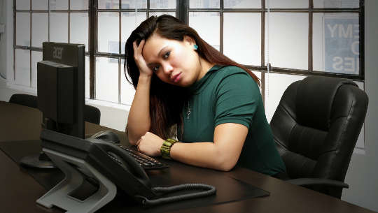 woman sitting at her desk looking worried