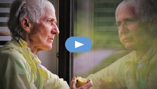 older person eating an apple and looking at her reflection in a window