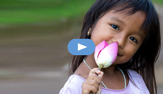 smiling young girl holding an unopened lotus flower