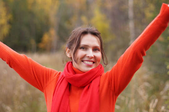 smiling young woman dressed in red with her arms up in victory