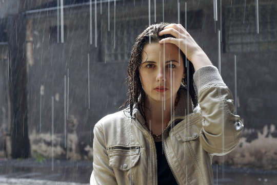 young woman standing under the rain