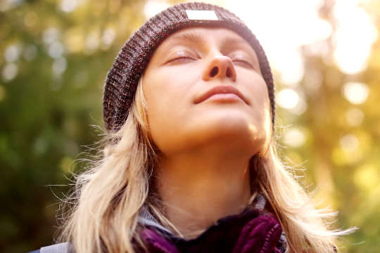 young woman with her eyes closed, face up to the sky