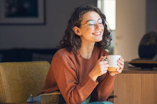 a cheerful young woman holding a cup