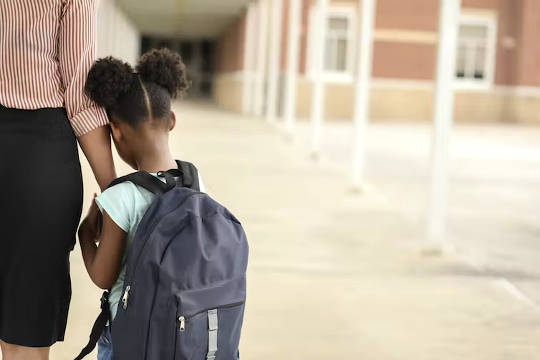 a mother holding her daughter's hand as she returns to school