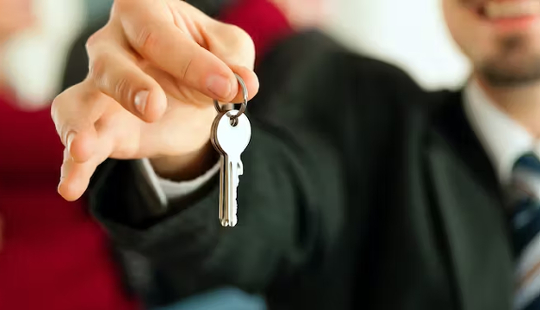 a realtor holding out a key to someone