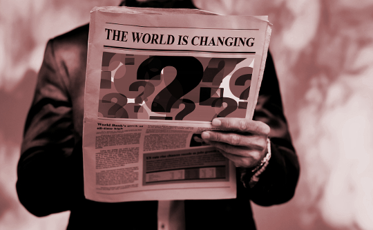 a man reading a newspaper with the headline "The World is Changing"