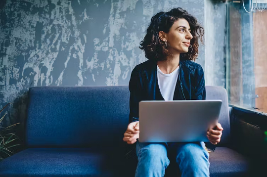 woman sitting in front of a laptop looking off into the distance