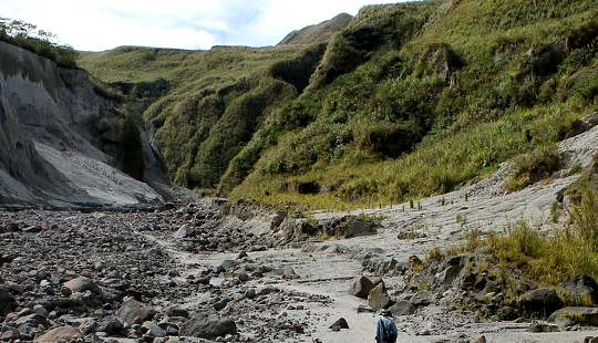 a rough trail in the mountains with a lone hiker