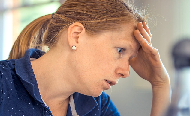 tired-looking woman with her hand on her forehead