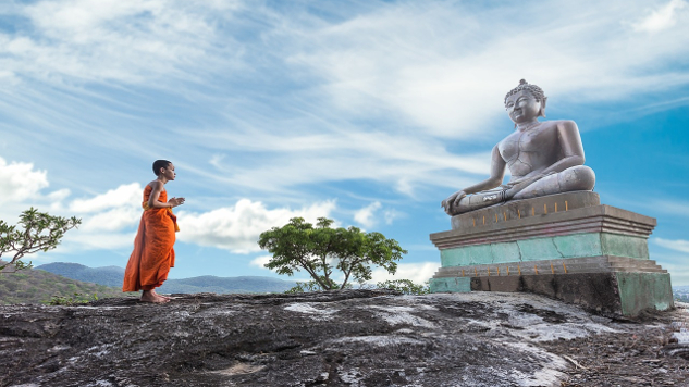 statue of buddha with a young monk standing in front