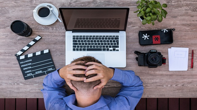 man sitting in front of his laptop with his hands behind his head