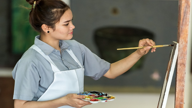 a young woman painting on an easel