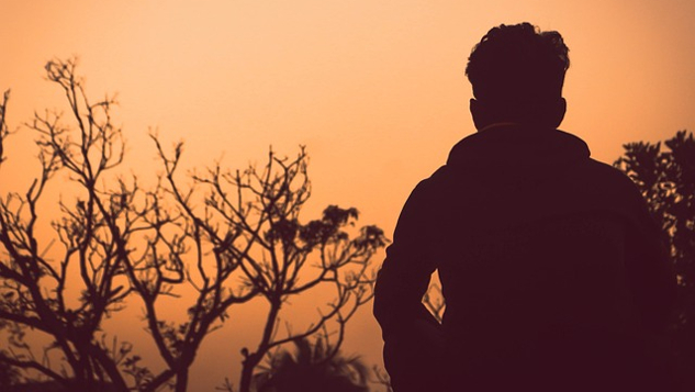 man standing alone outside at sunset