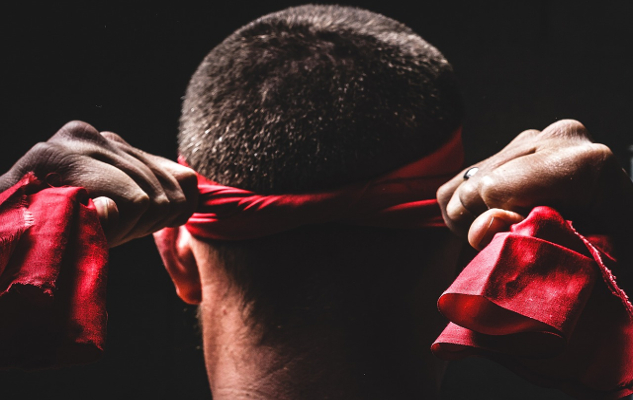 a man tying a blindfold over his eyes