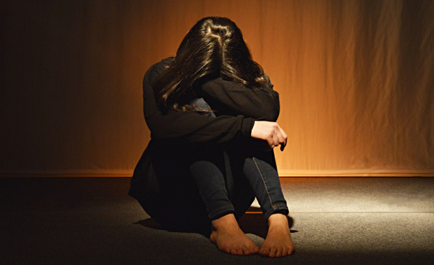 woman sitting on the floor with her face covered by her arms