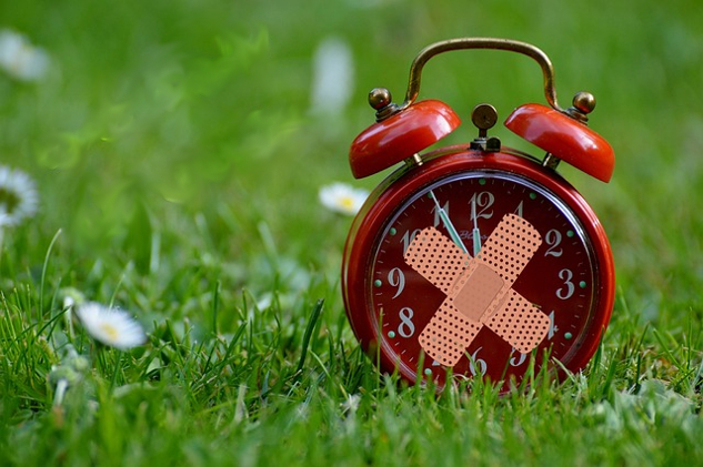 an old-style alarm clock with two bandaids over the face in the shape of an X