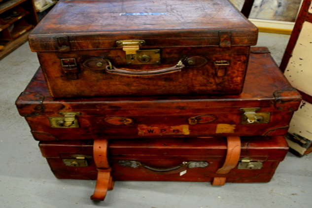 three unbuckled old suitcases stacked on top of each other