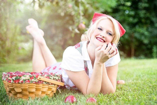 pretty woman outside laying on the grass smiling