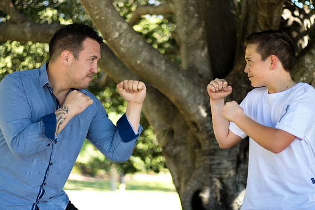 a father and son facing each other wearing boxing gloves