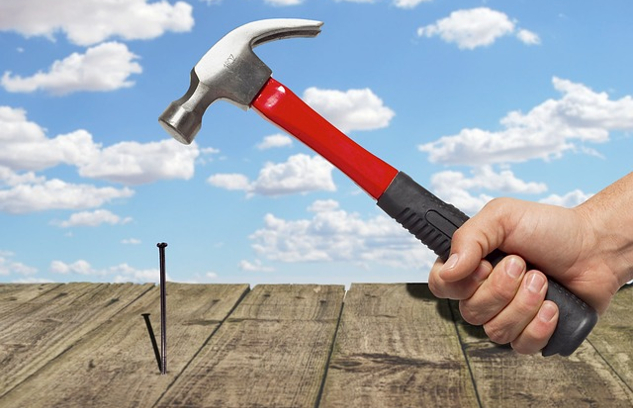 a hand holding a hammer and getting ready to strike a nail