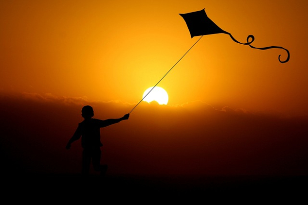 a child flying a kite under the bright shining sun