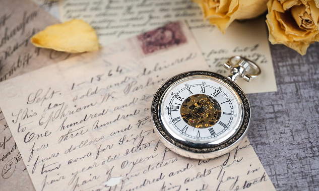 a pocket watch resting on a hand-written letter