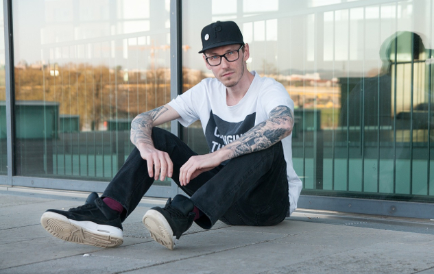 a working class man sitting on the ground in front of a fence