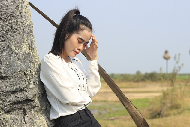 woman standing outside holding her hand on her forehead