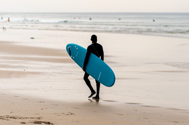 man walking out to the ocean with his surfboard