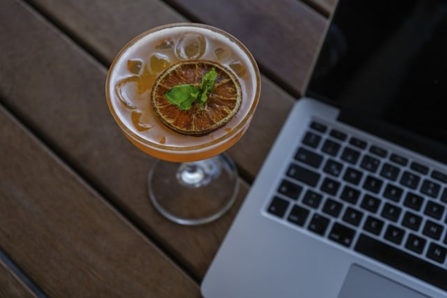 open laptop with a cocktail next to it