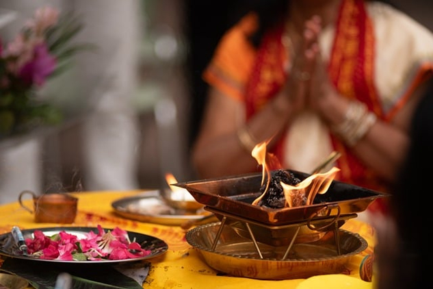 a person in meditation in front of a bowl of flower petals and a bowl of fire