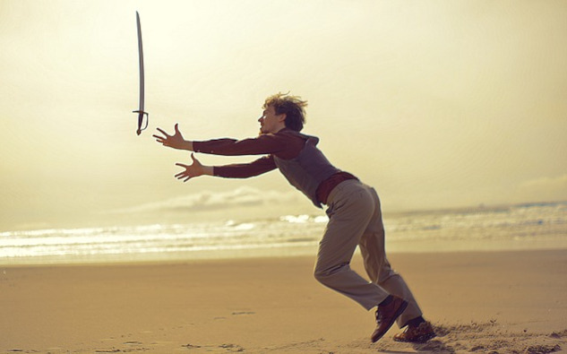 a man on a beach playing with a sword