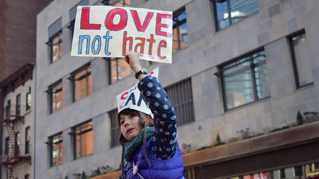 a young woman holding up a sign that reads: Love not Hate