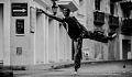 man dancing in the street with his hand pointing to a sign with an arrow in his direction