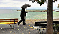 two persons walking with one holding an umbrella over both of them