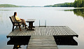 woman sitting on a bench on a platform dock surrounded by a very calm lake