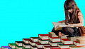 Young girl sitting surrounded by lots of book of various colors