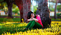 young woman sitting under a tree with her eyes closed