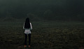 woman standing alone facing a bank of fog