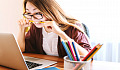 young woman at her laptop biting down hard on a pencil